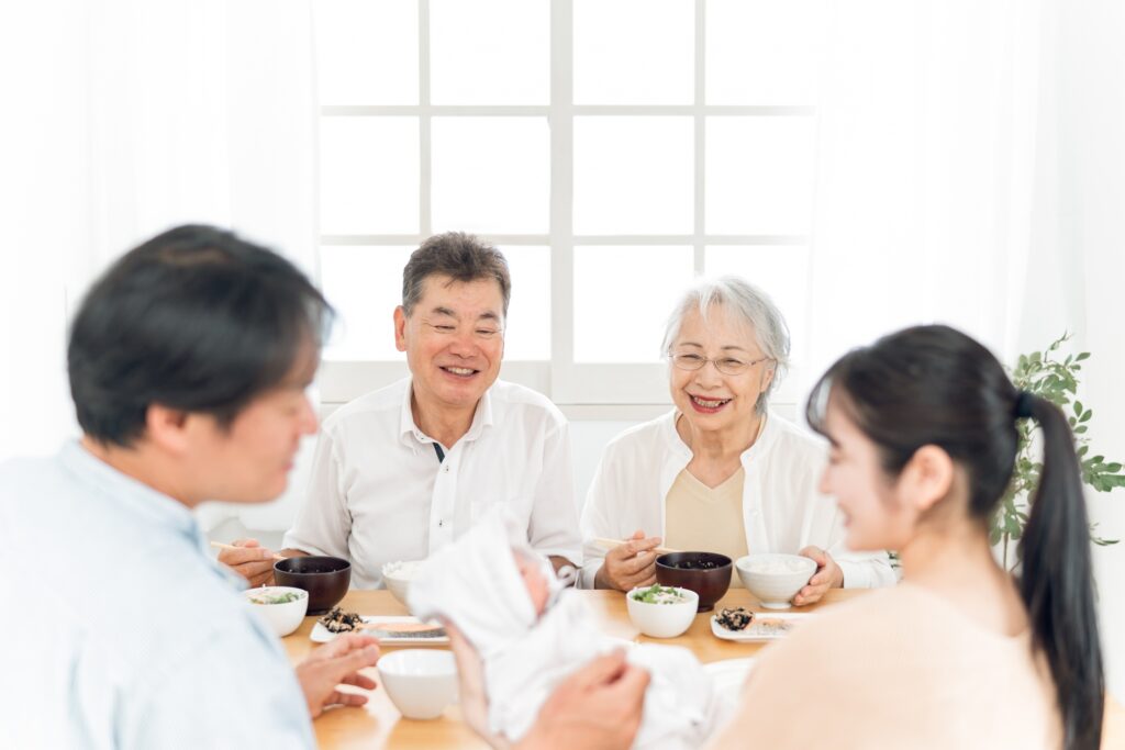 食卓で談笑する夫婦と両親