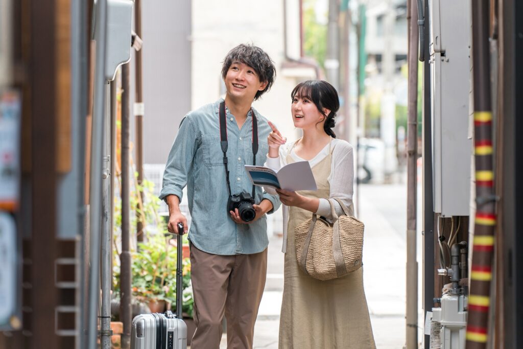 カメラとスーツケースを持って街を歩く夫婦